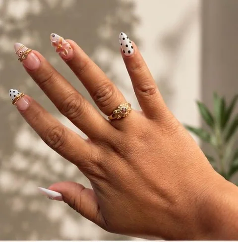 White and pink nail art with polka dots, gold details, and a floral accent